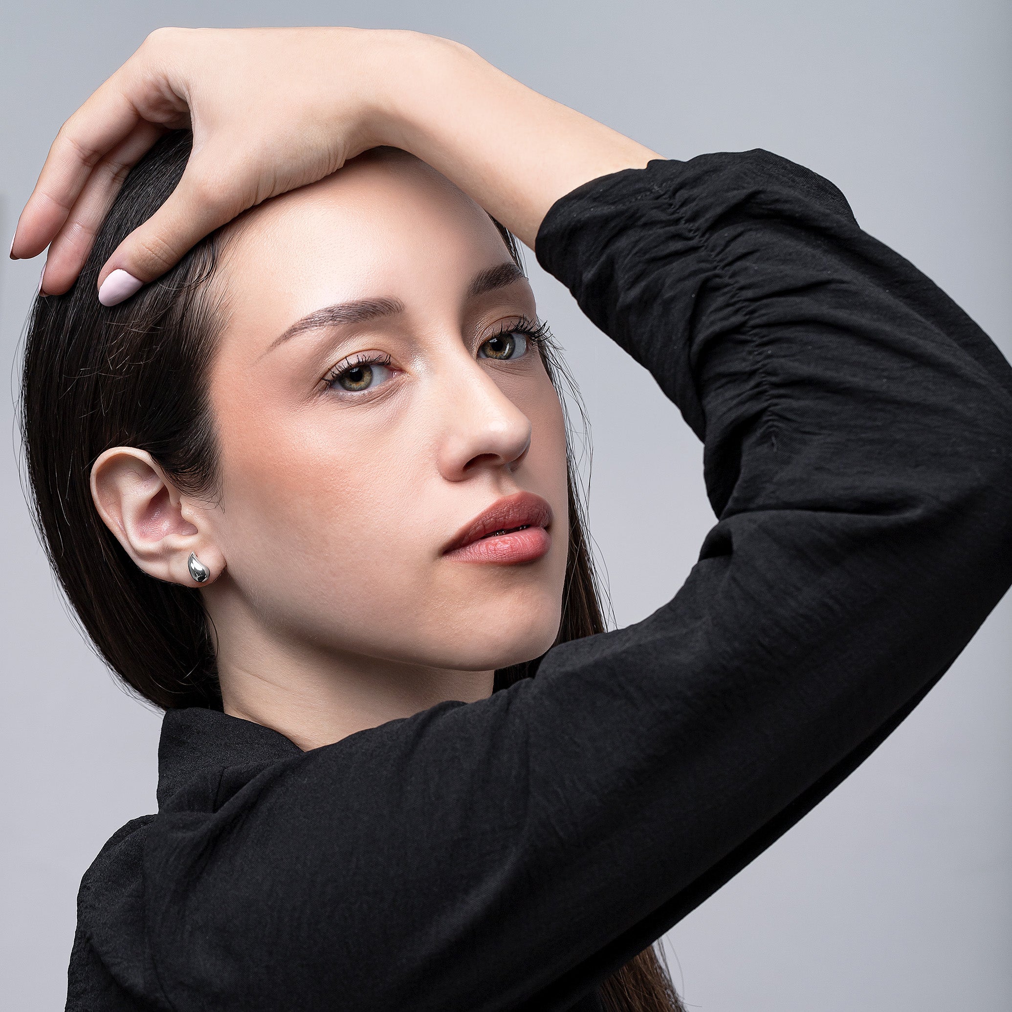 Woman with short hair touching her head against a gray background
