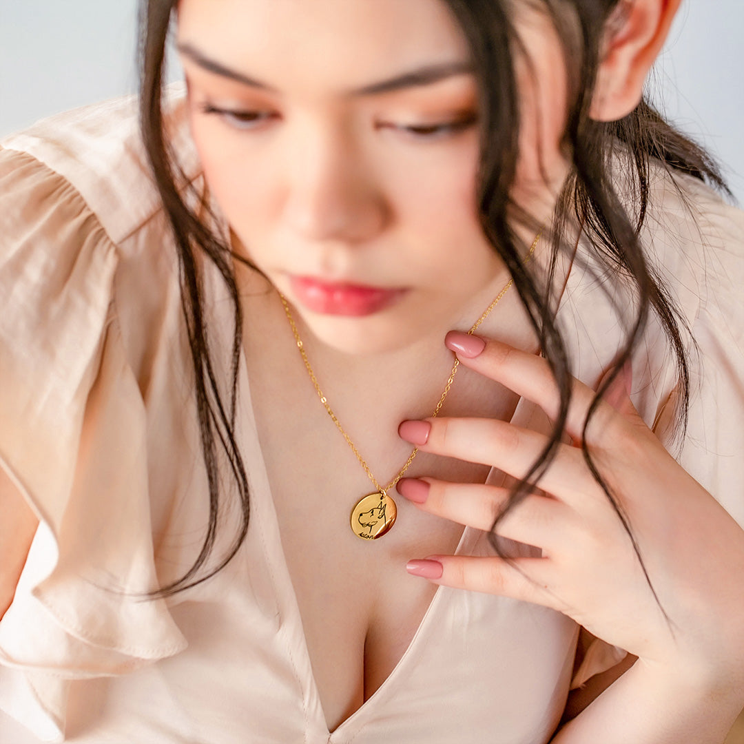 Woman wearing a gold pet silhouette necklace engraved with a dog breed and name