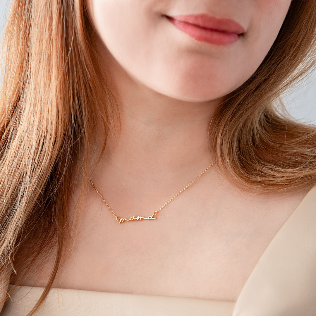 Mama script necklace worn on neck, gold finish