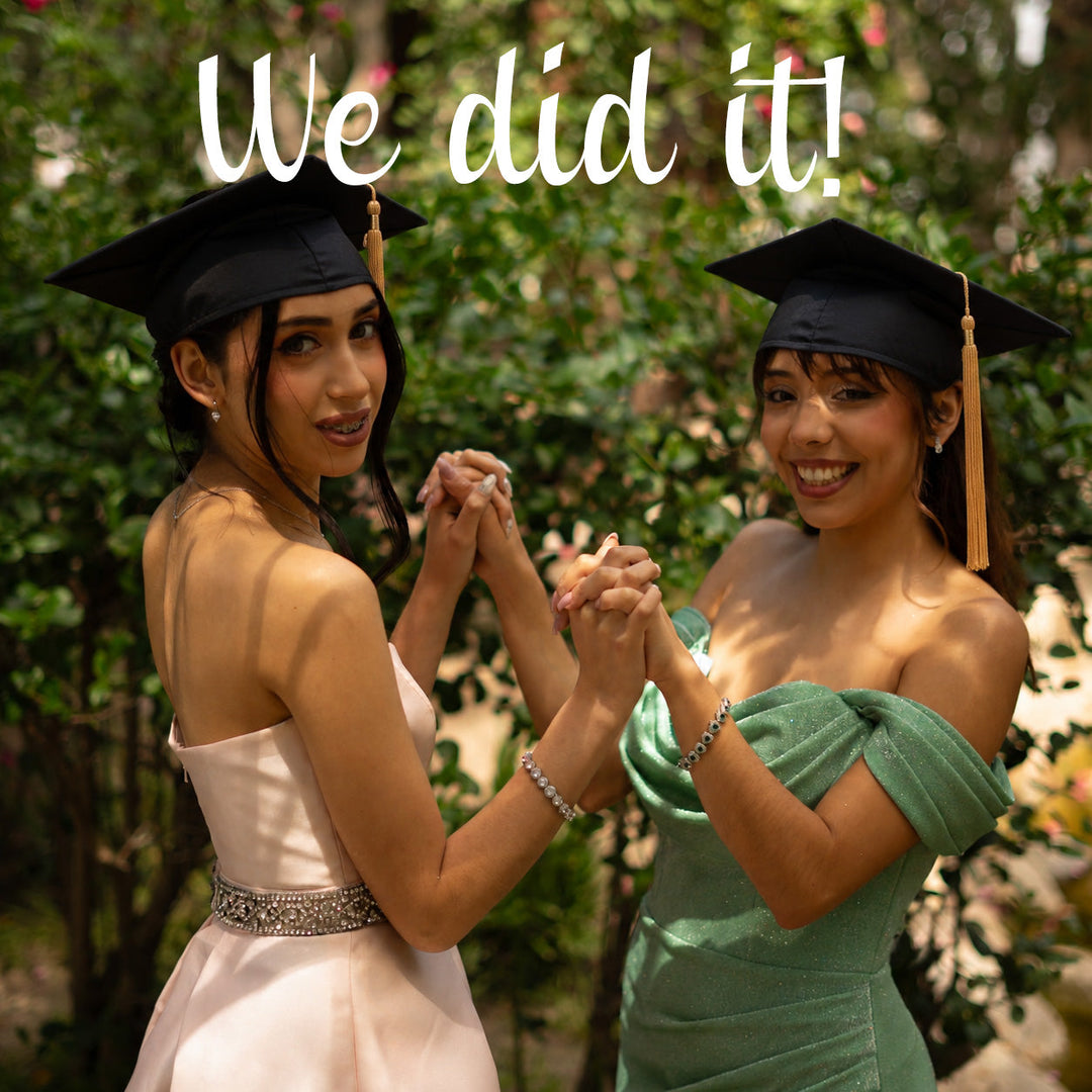 Two young women in graduation caps and formal dresses — one in blush pink, one in sage green — holding hands and smiling outdoors among lush greenery, with the text "We did it!" overlaid at the top.