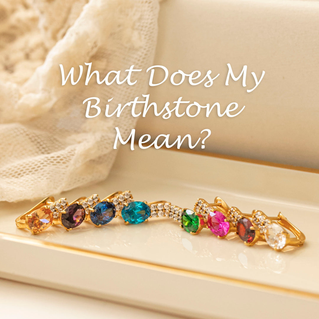 gold birthstone earrings in multiple colors displayed on a cream tray
