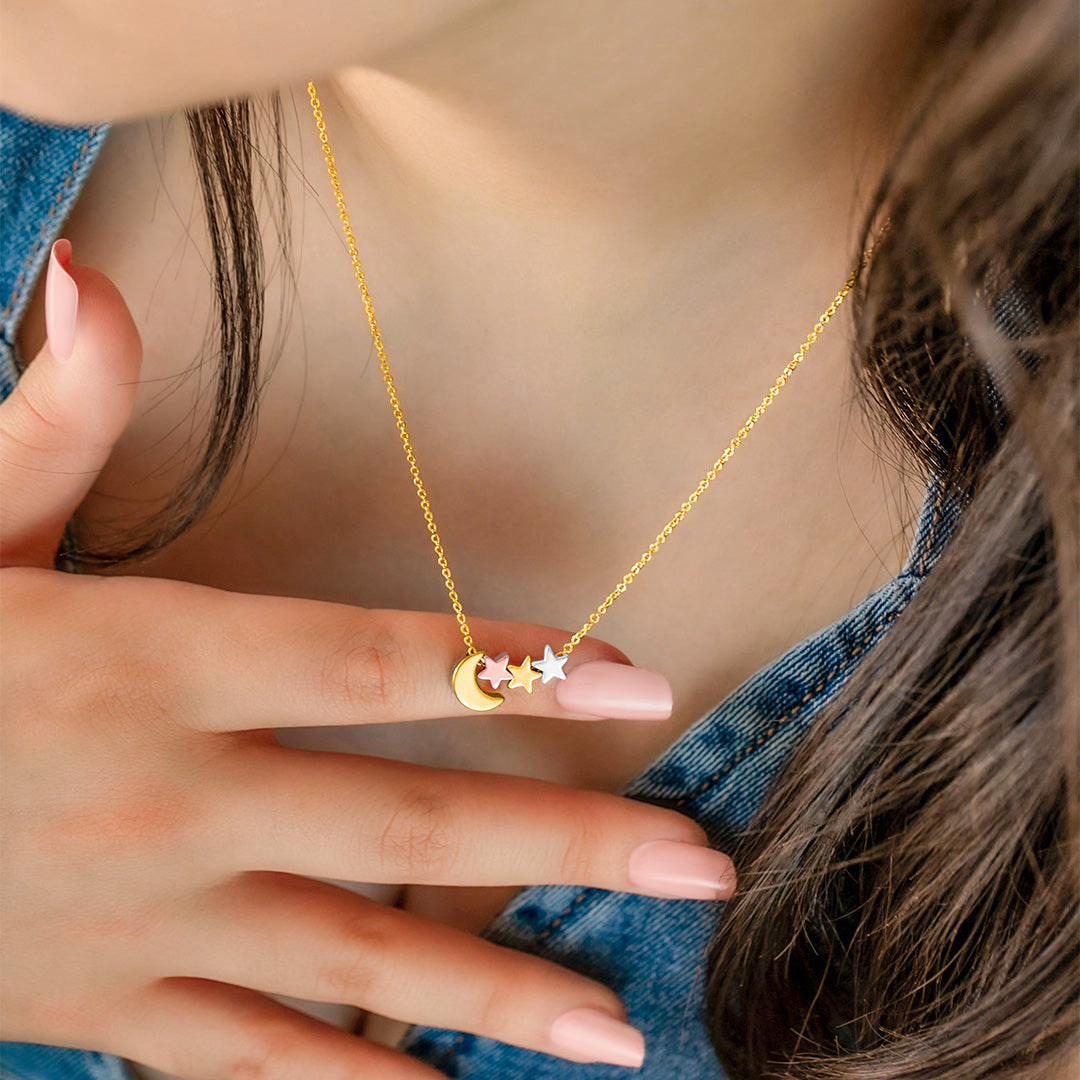 Moon and star necklace worn on neck, gold with mixed metal star charms