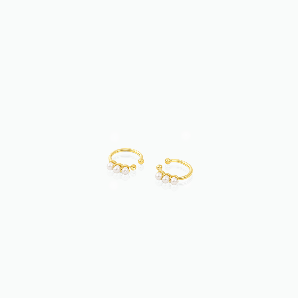 Gold ear cuffs with small pearls on a white background