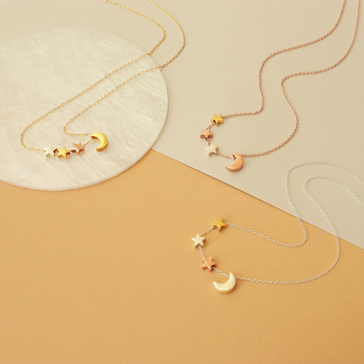 Three celestial necklaces in gold-, rose-gold-, and silver tones with crescent moon and star charms