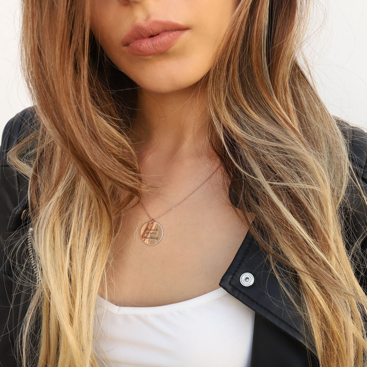 Rose-gold-tone round pendant necklace with handwritten-style engraving worn at the neckline