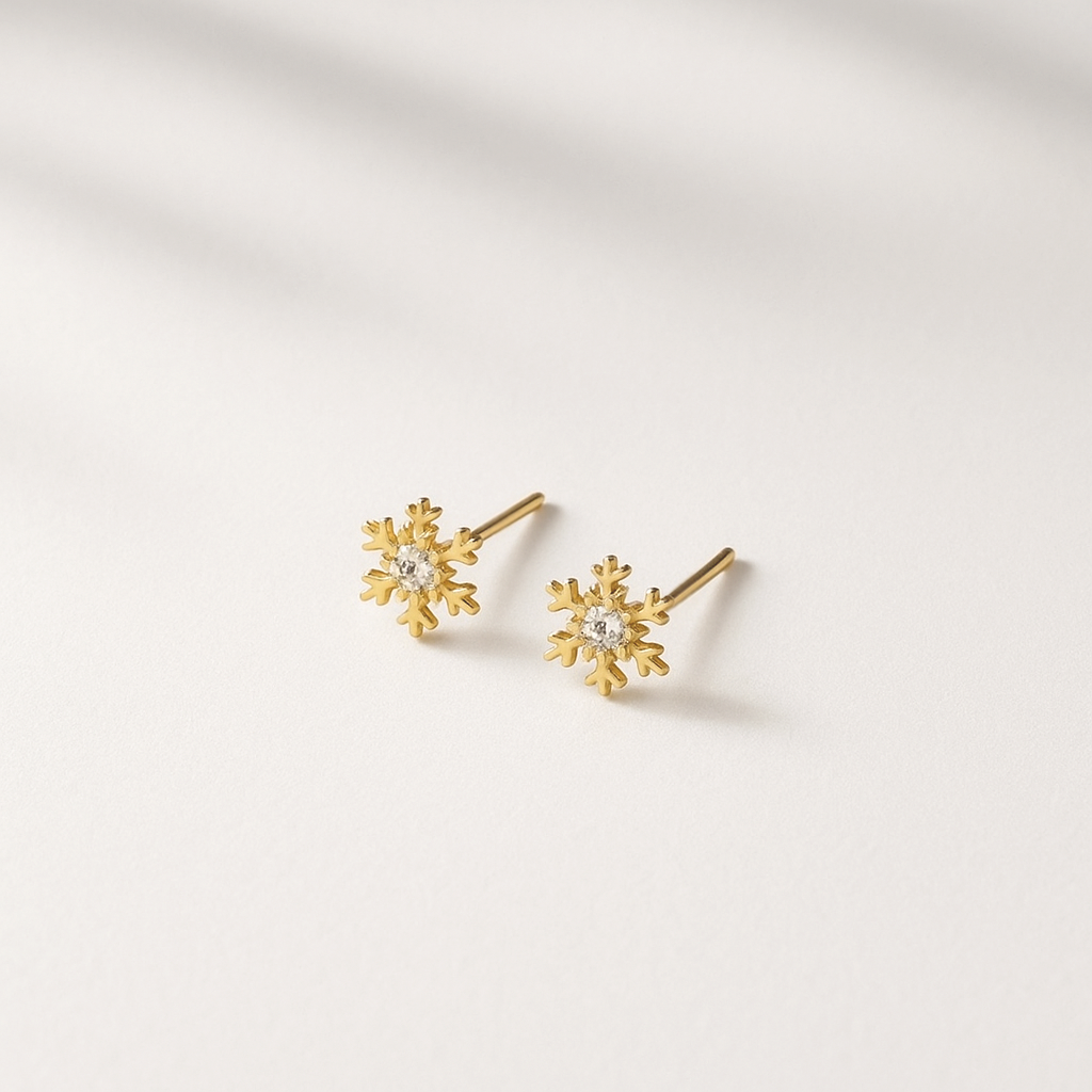 Gold snowflake-shaped earrings on a light background