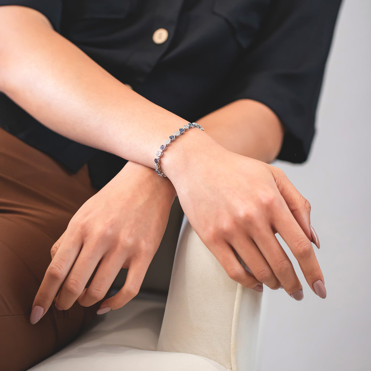 Silver-tone bracelet with alternating round and oval sparkling links worn on a wrist