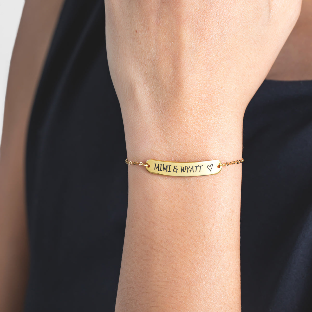 Gold-tone bar bracelet engraved MIMI & WYATT with a heart, worn on a wrist