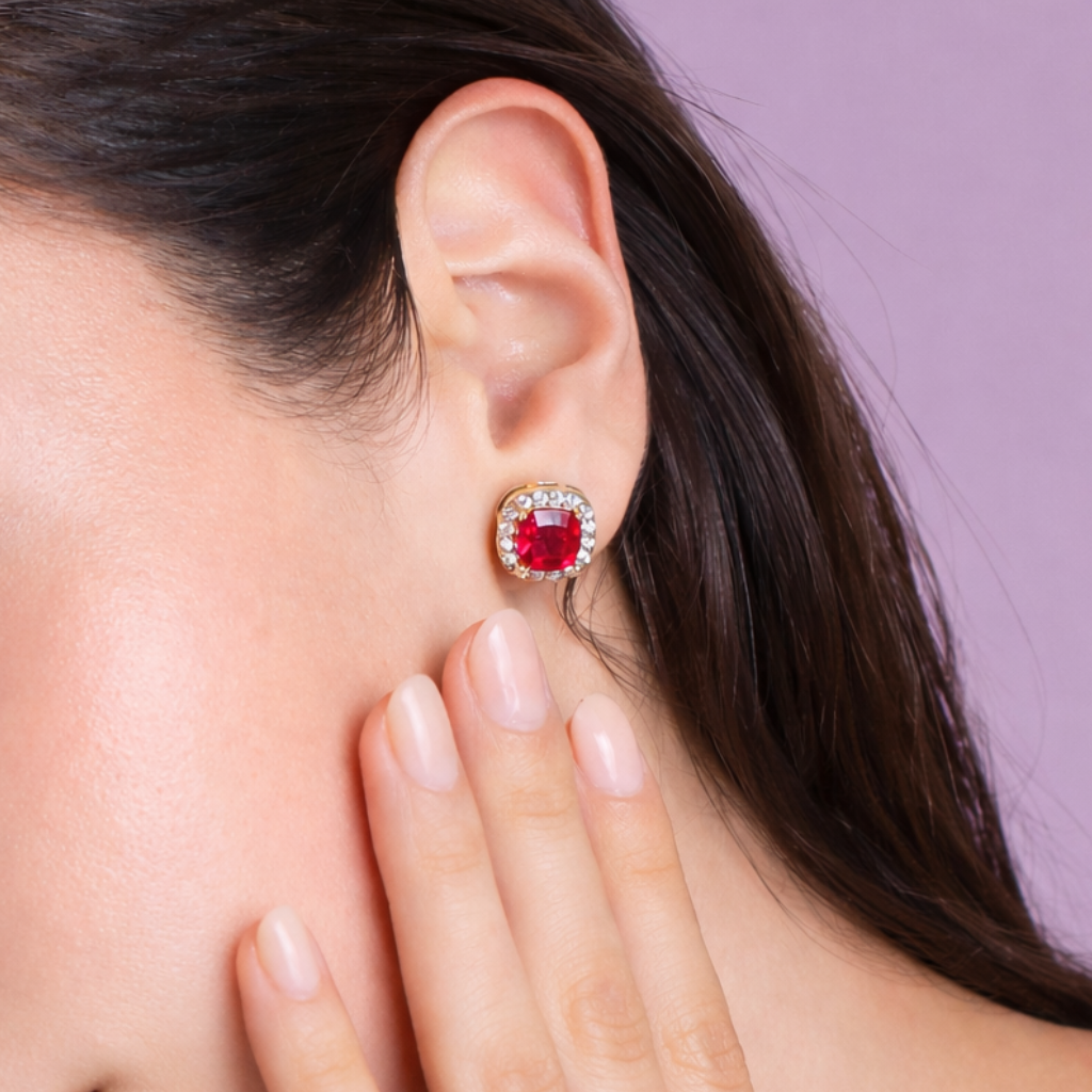 Close-up of a woman wearing a red gemstone earring against a purple background
