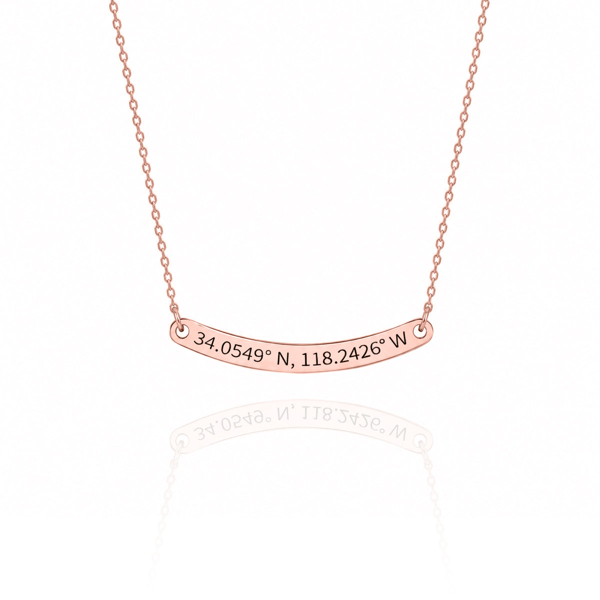 Rose-gold-tone curved bar necklace engraved 34.0549° N, 118.2426° W on a white background