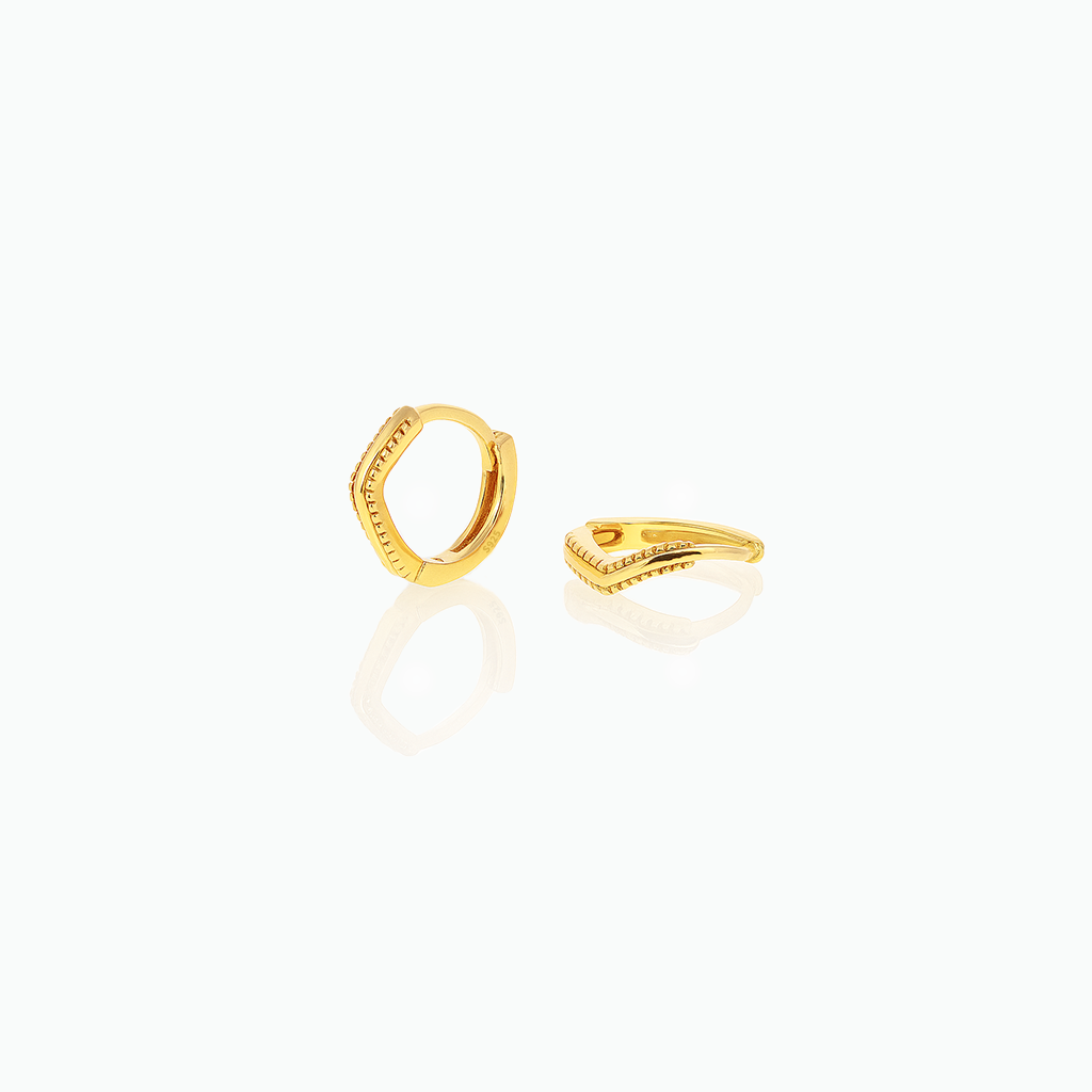 Gold-tone huggie hoop earrings with angled textured fronts displayed on a white background