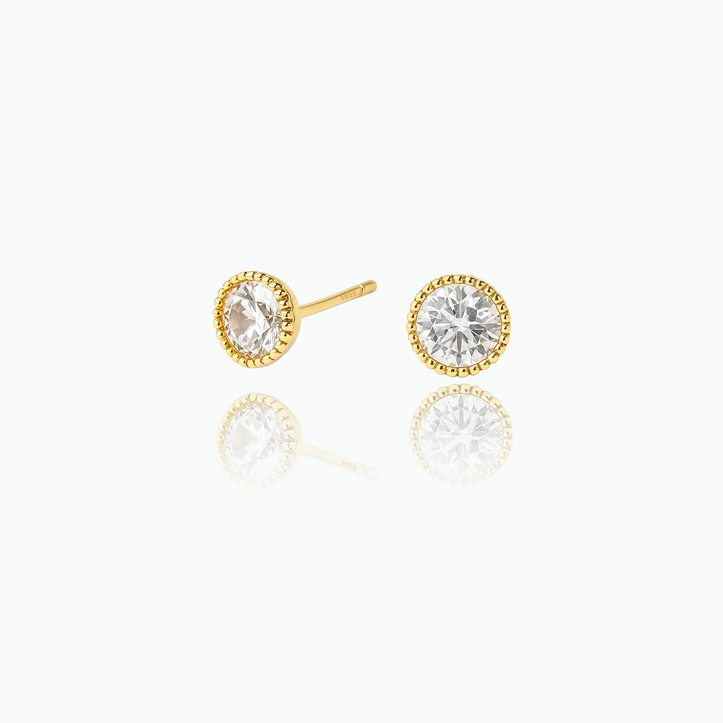 Gold earrings with clear gemstones on a white background