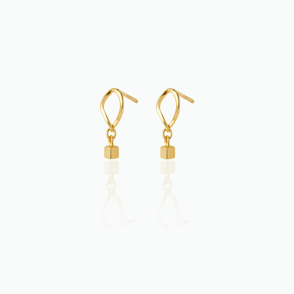 Gold earrings with cube-shaped drops on a white background