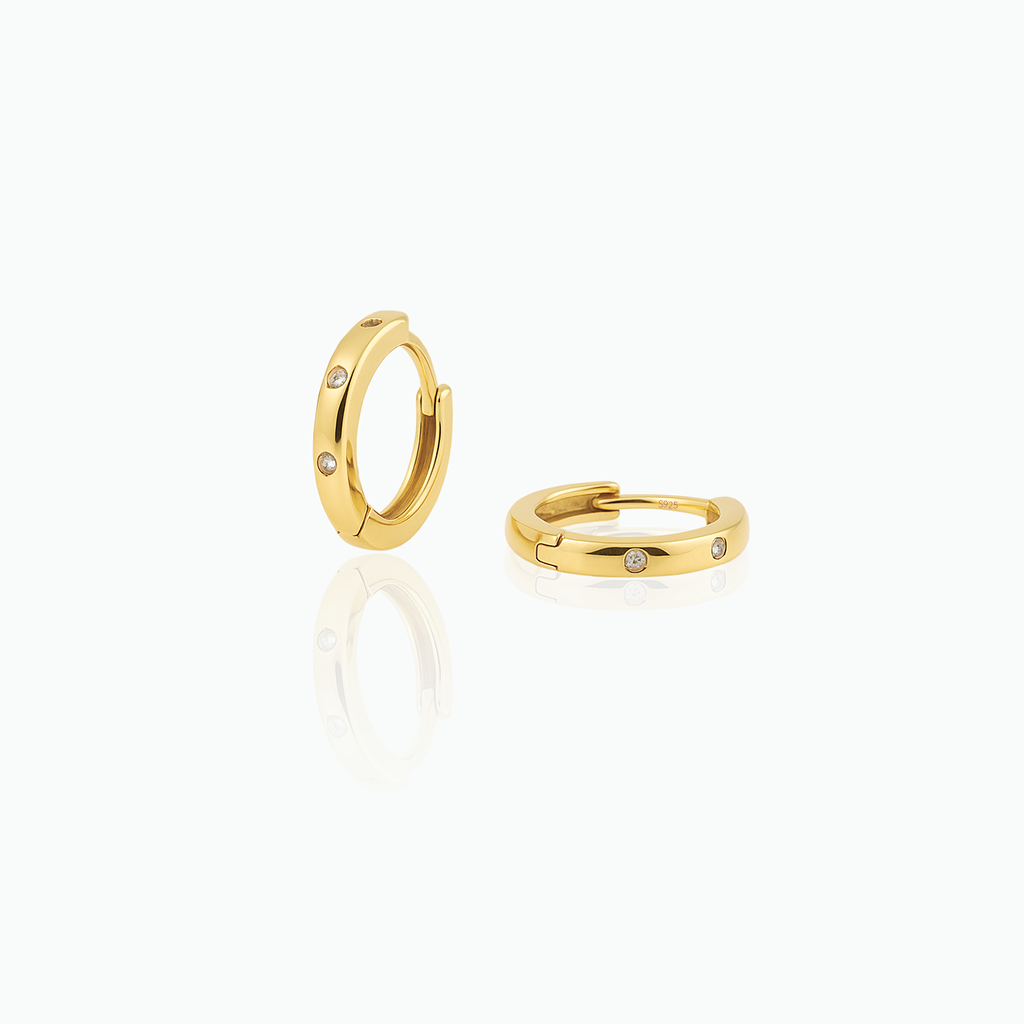 Gold hoop earrings with small diamonds on a white background