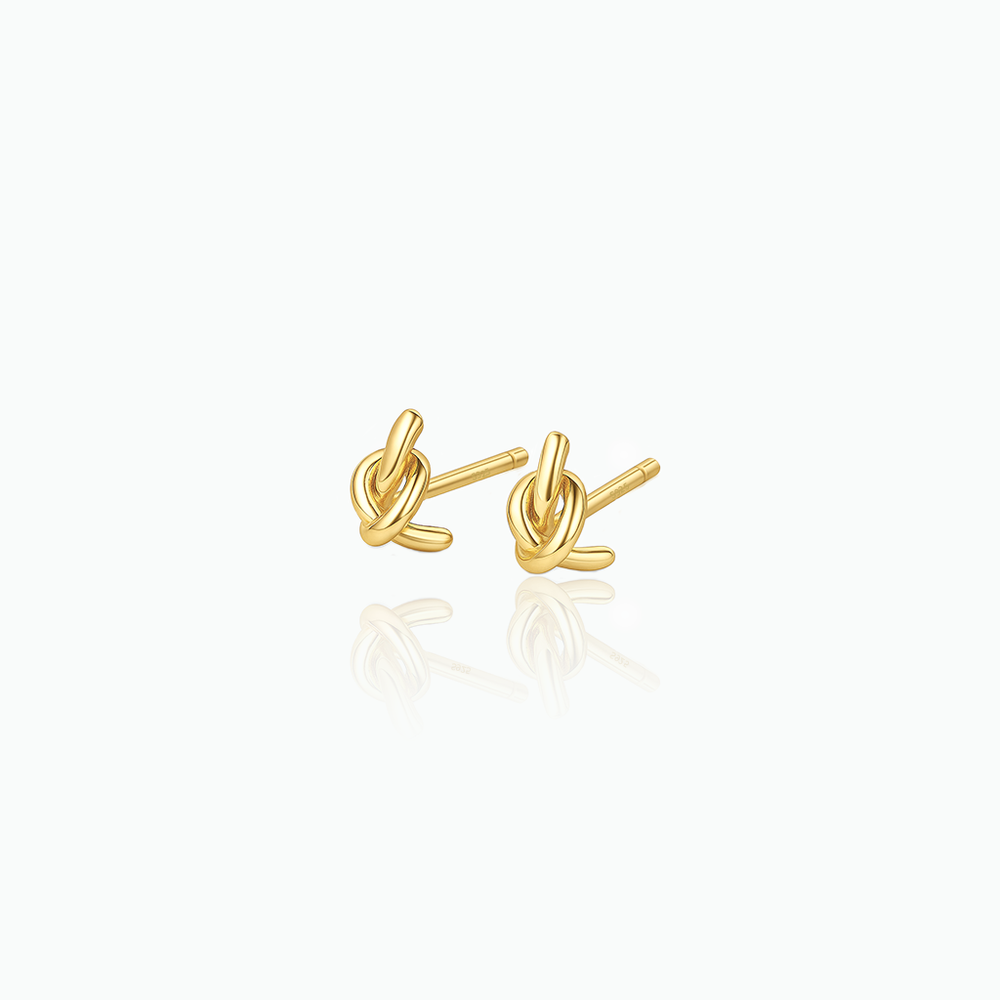 Pair of gold knot earrings on a white background