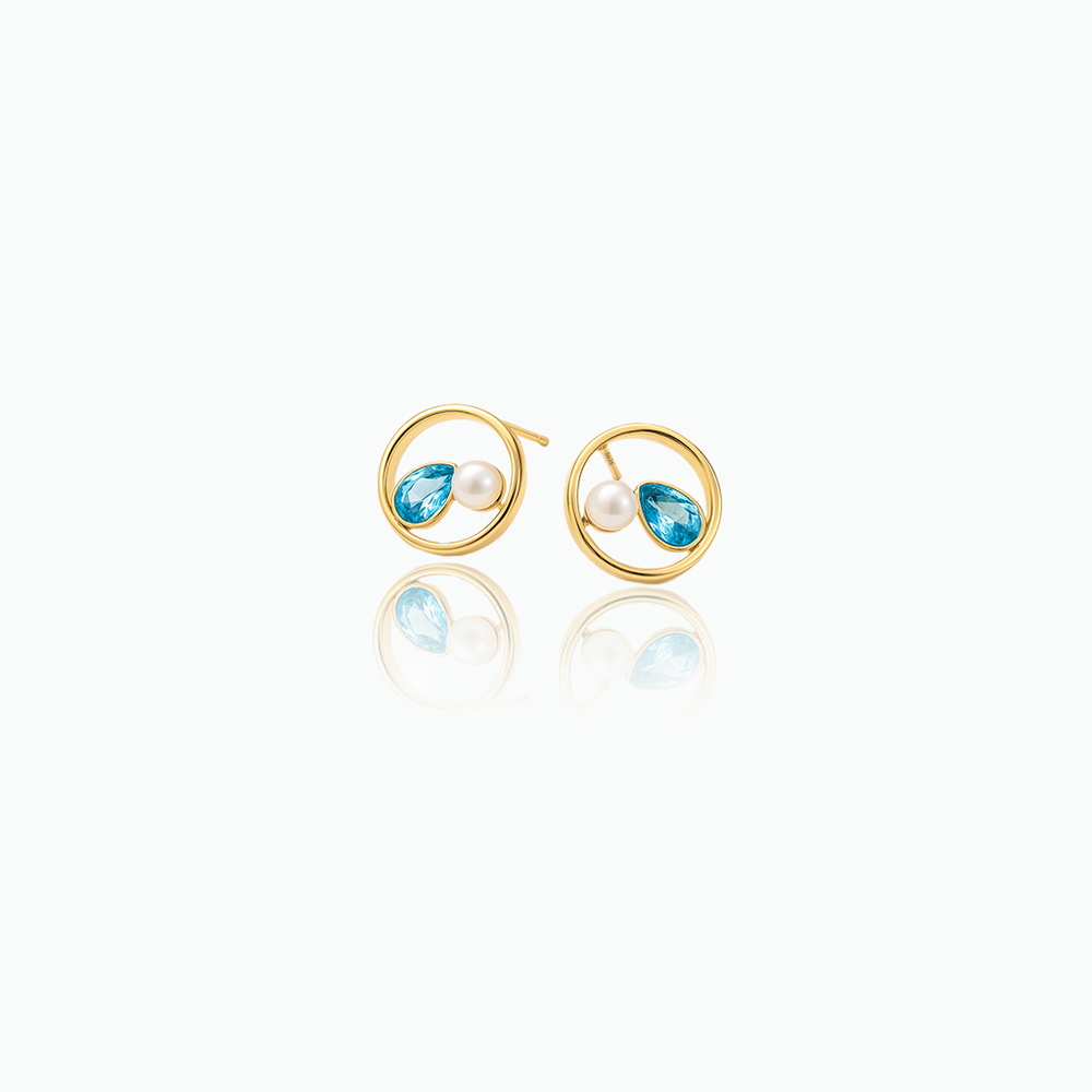 Gold earrings with blue gemstones and pearls on a white background