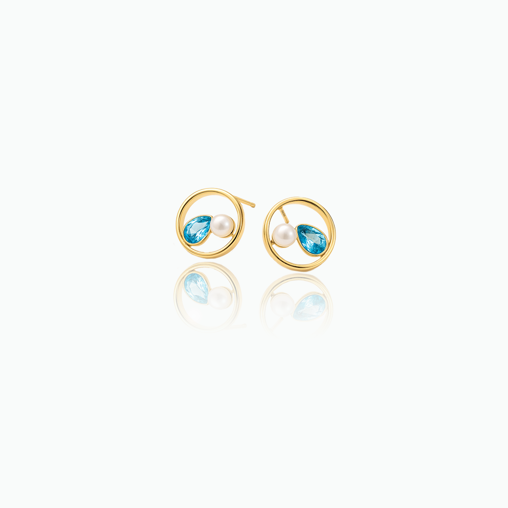 Gold earrings with blue gemstones and pearls on a white background