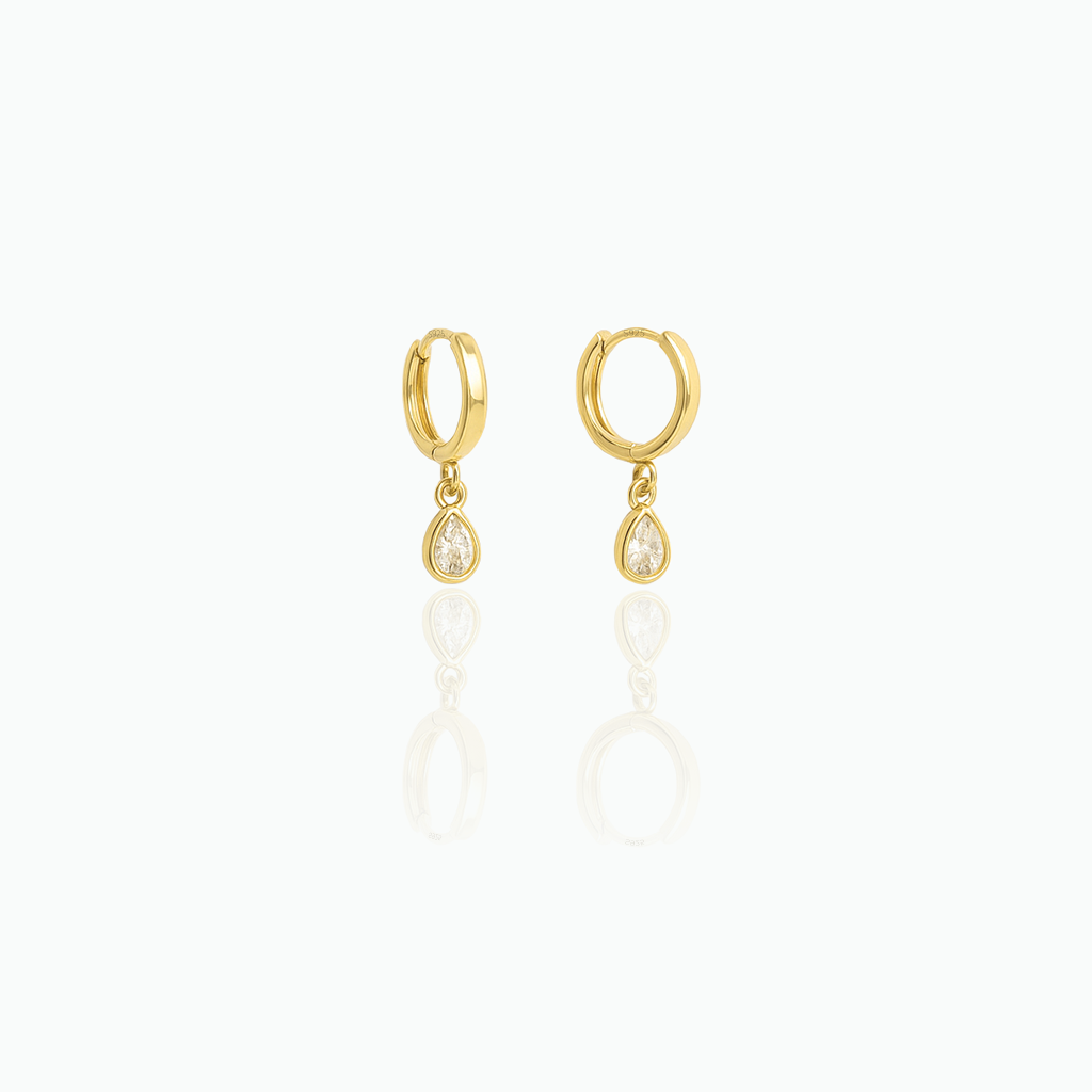 Gold-tone dangle huggie hoop earrings with clear teardrop stones on a white background