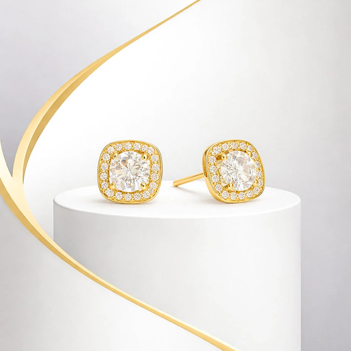 Gold earrings with clear gemstones on a white and gold stand