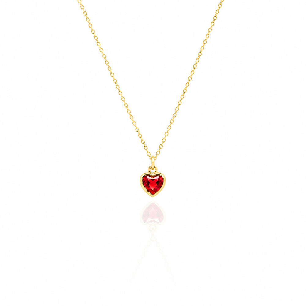 Gold necklace with a red heart-shaped pendant on a white background