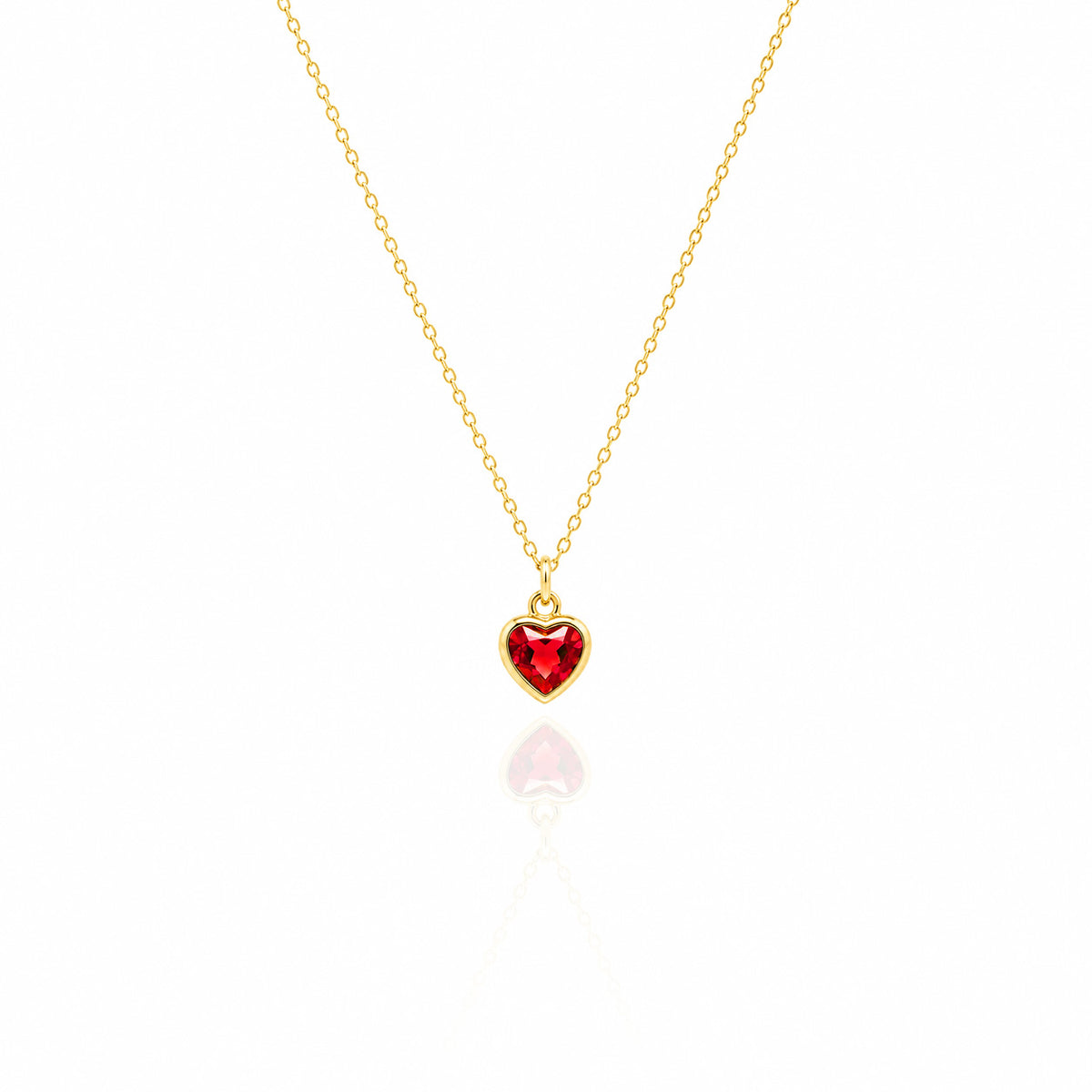 Gold necklace with a red heart-shaped pendant on a white background