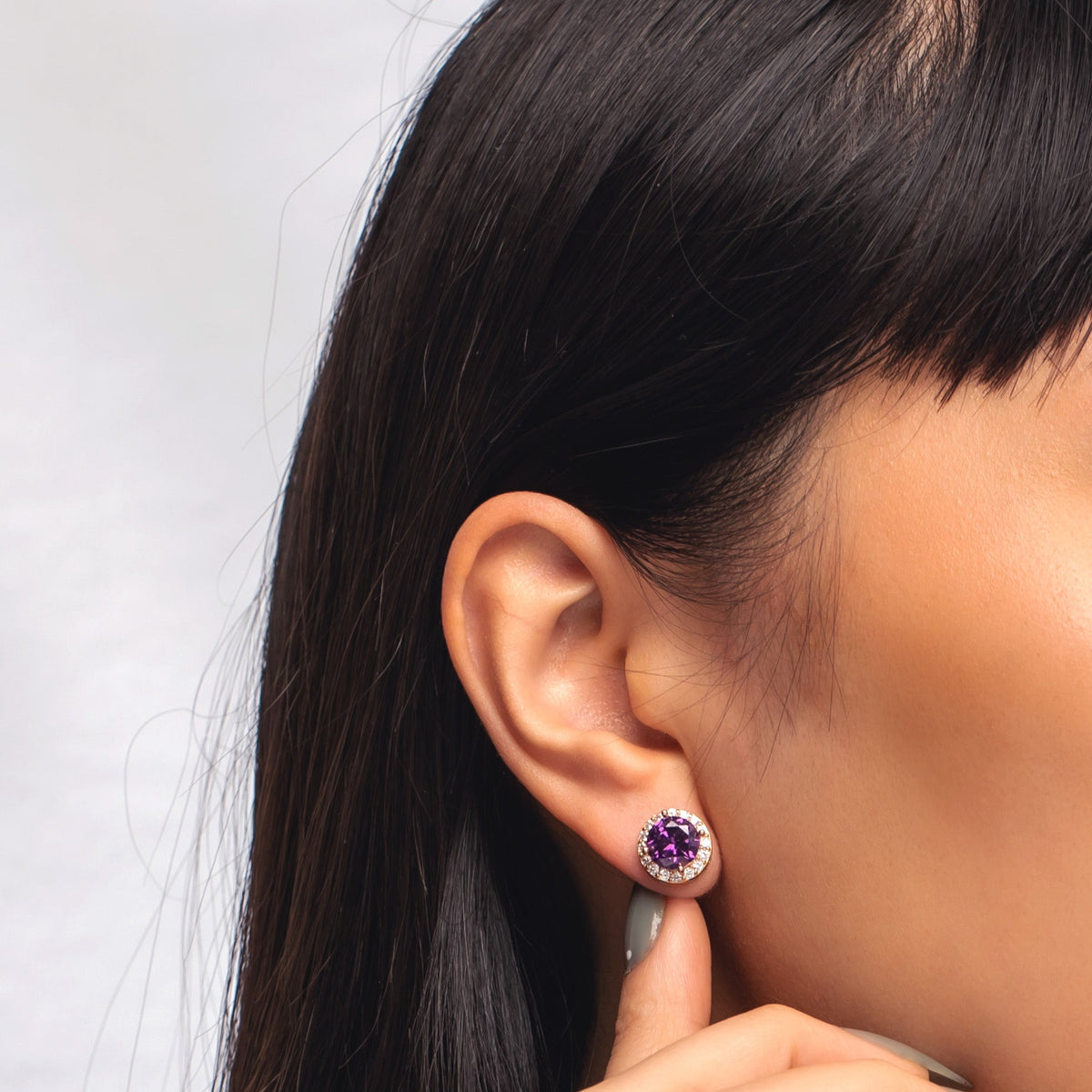 Close-up of model wearing a purple bezel birthstone stud earring
