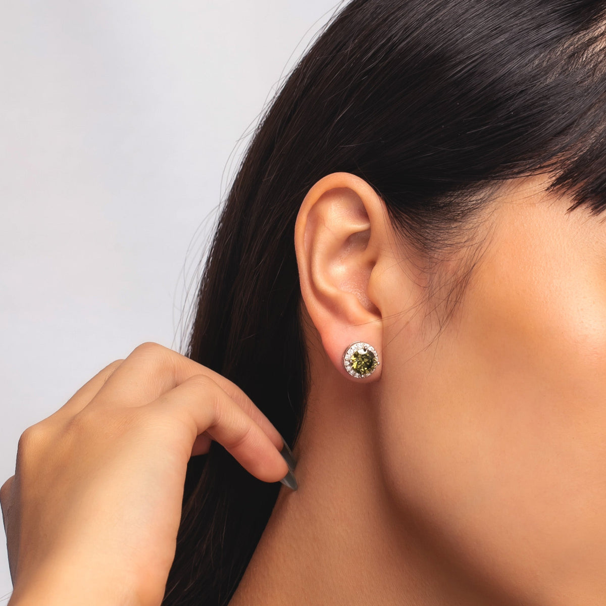 Close-up of model wearing a green bezel birthstone stud earring