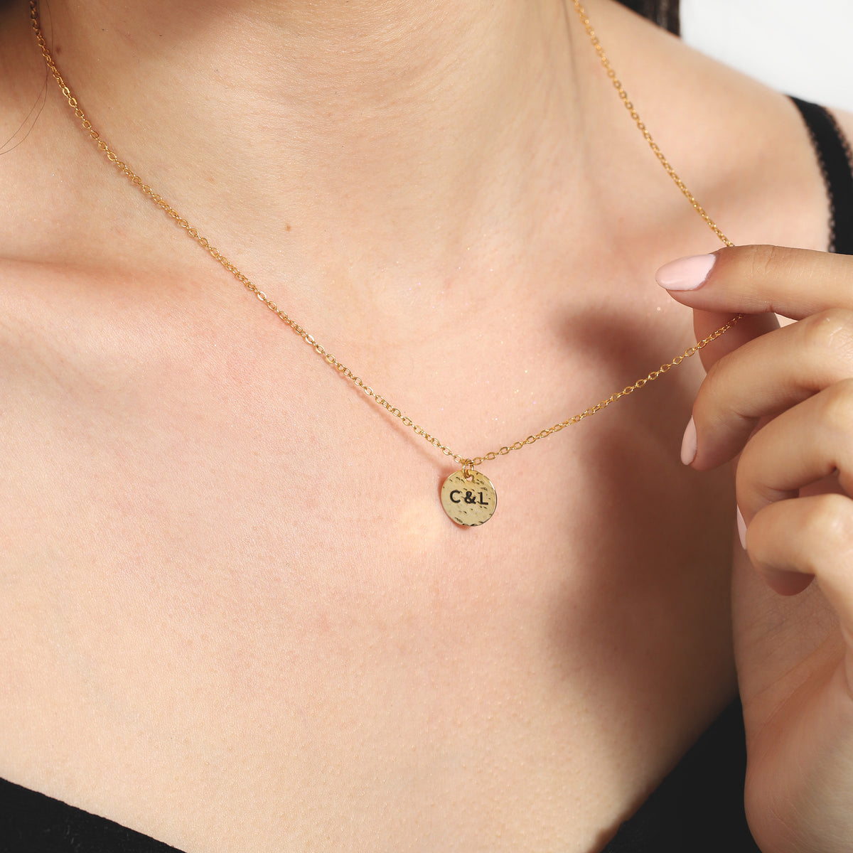 Gold-tone hammered disc necklace engraved with C&L, worn on the neck