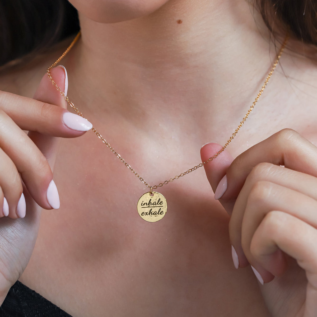 Gold-tone round disc necklace engraved inhale exhale worn at the neckline