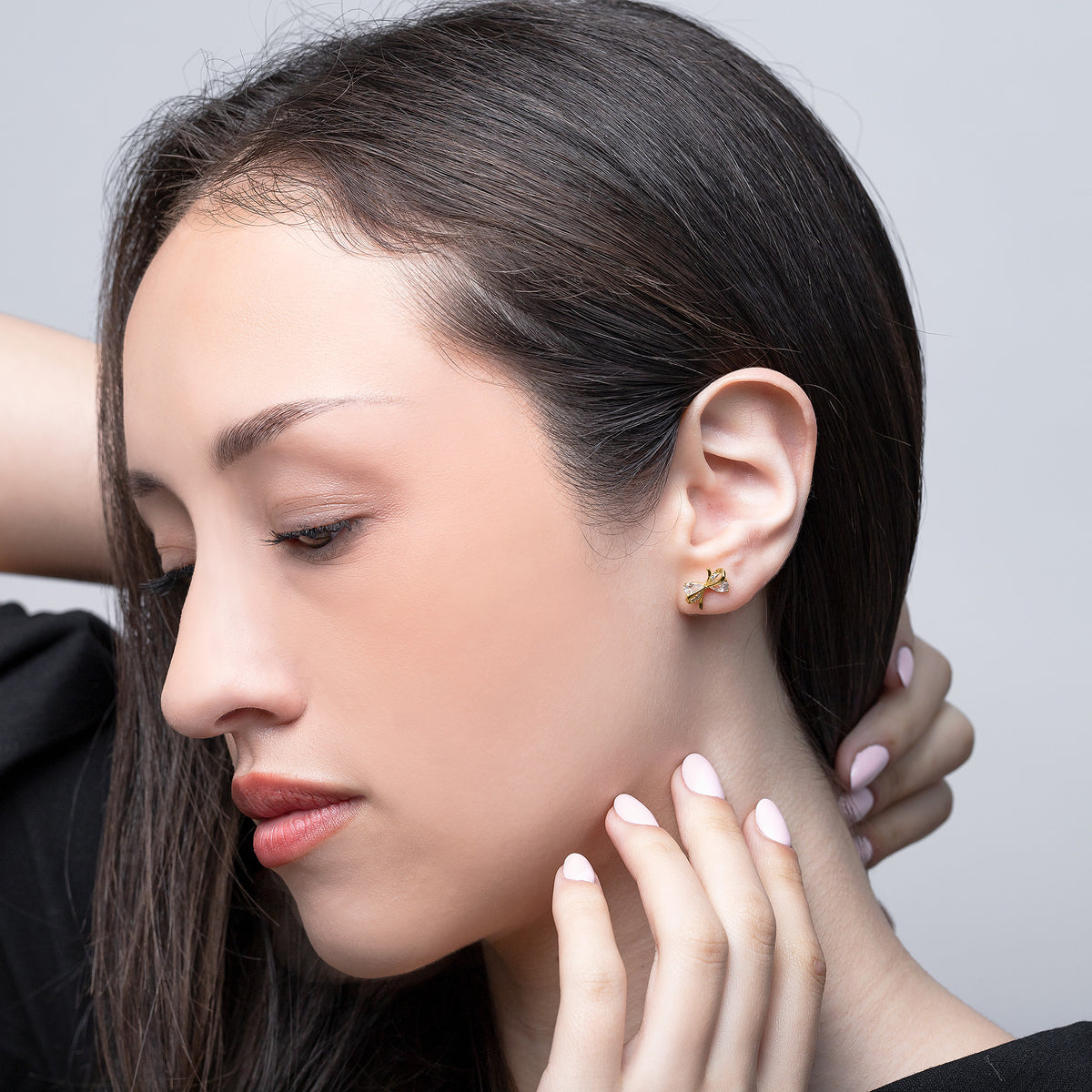 Close-up of a woman wearing gold earrings with a neutral background