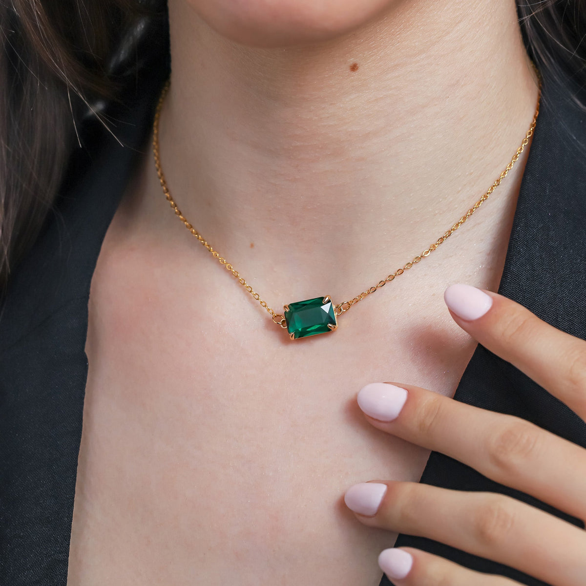 Gold-tone necklace with a rectangular green faceted pendant worn at the neckline
