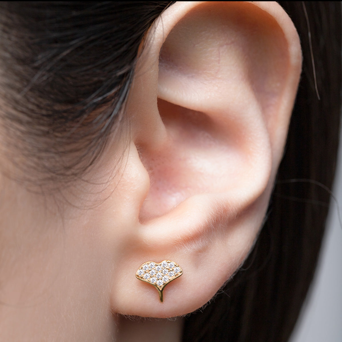Crystal-set whale tail stud earring worn on an ear in close-up