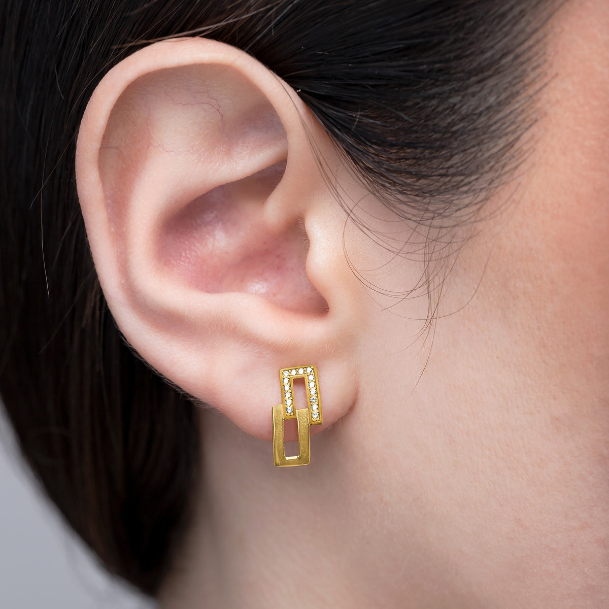 Gold hoop earrings worn by a person with a neutral background