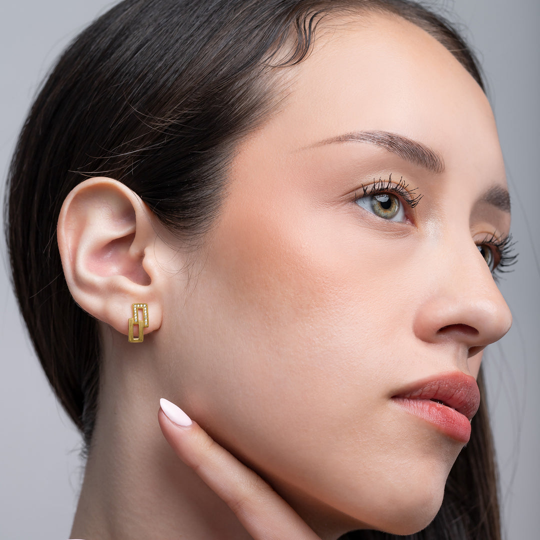 Close-up of a woman wearing a gold earring against a neutral background