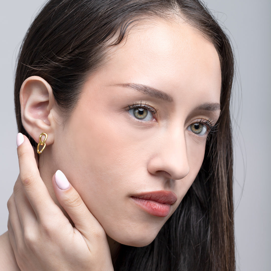Woman wearing a gold earring with a neutral background