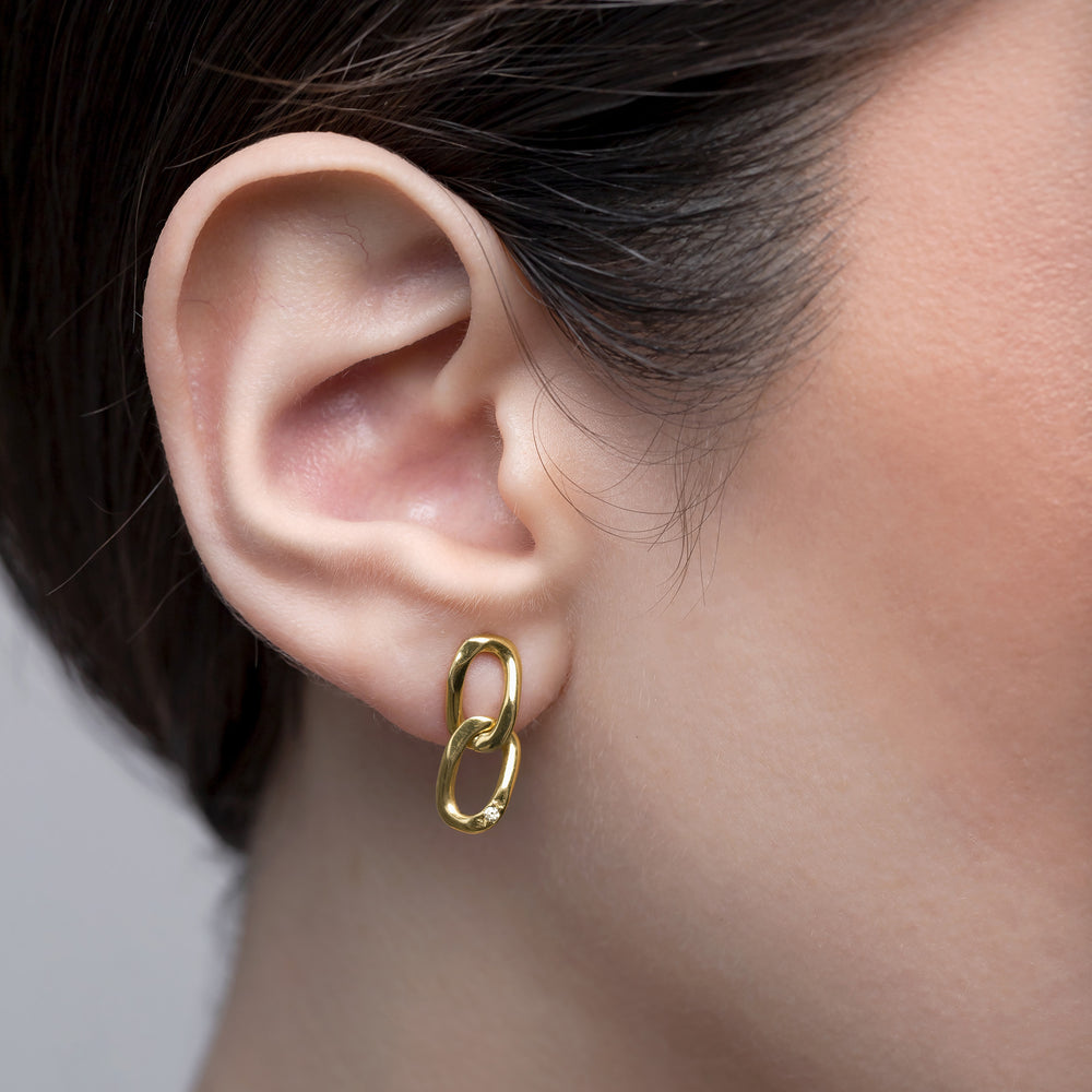 Gold hoop earring worn by a person with a neutral background