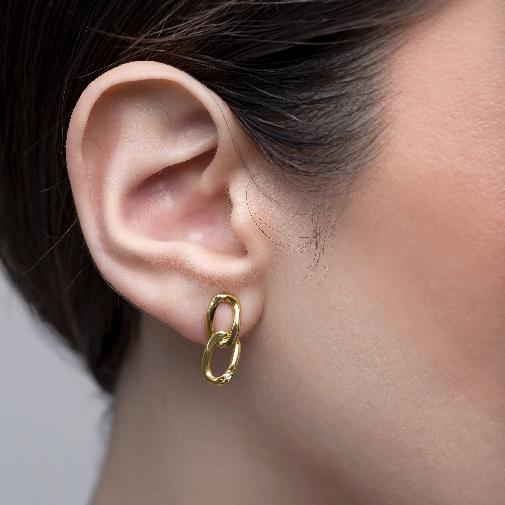 Gold hoop earring worn by a person with a neutral background