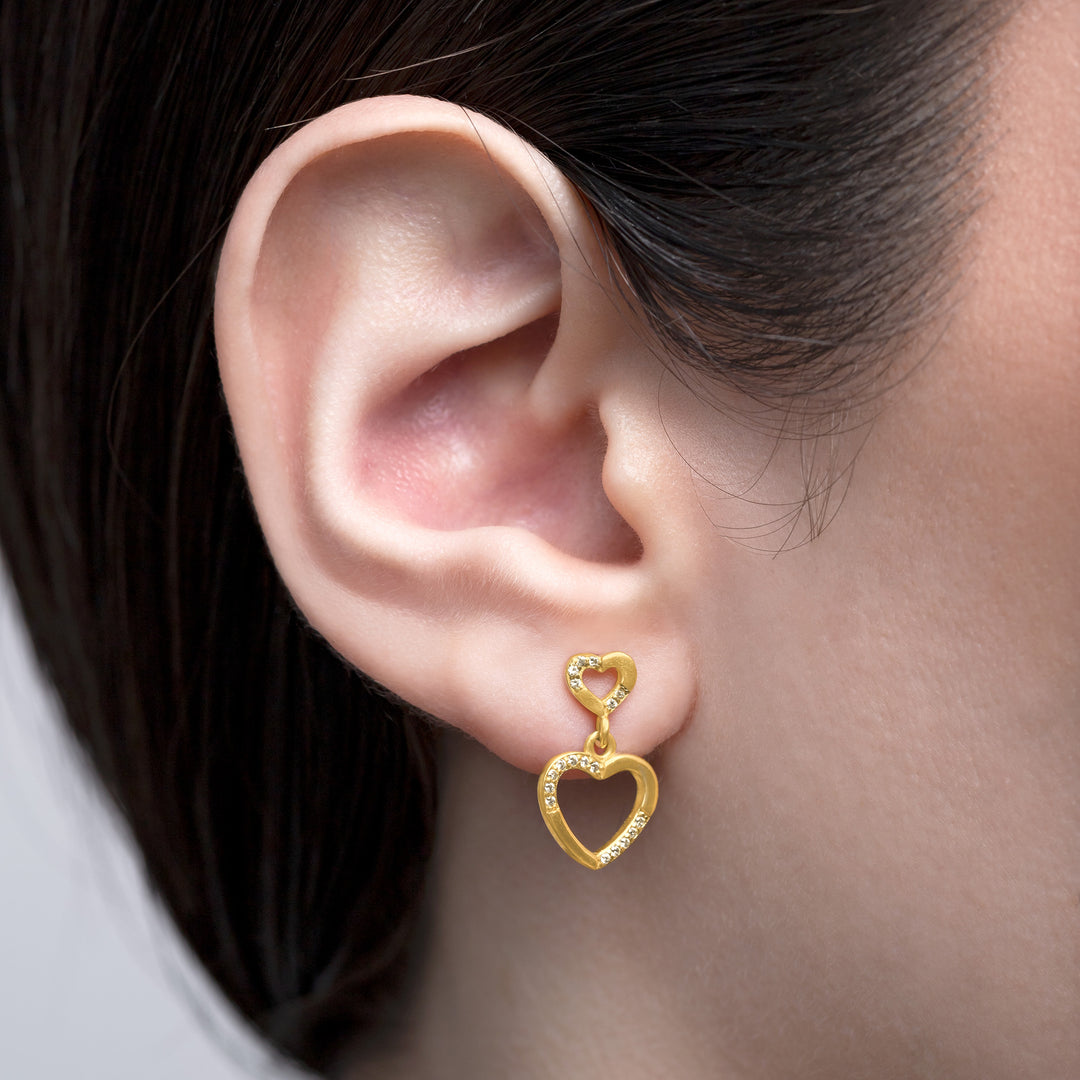 Gold heart-shaped earring worn by a person
