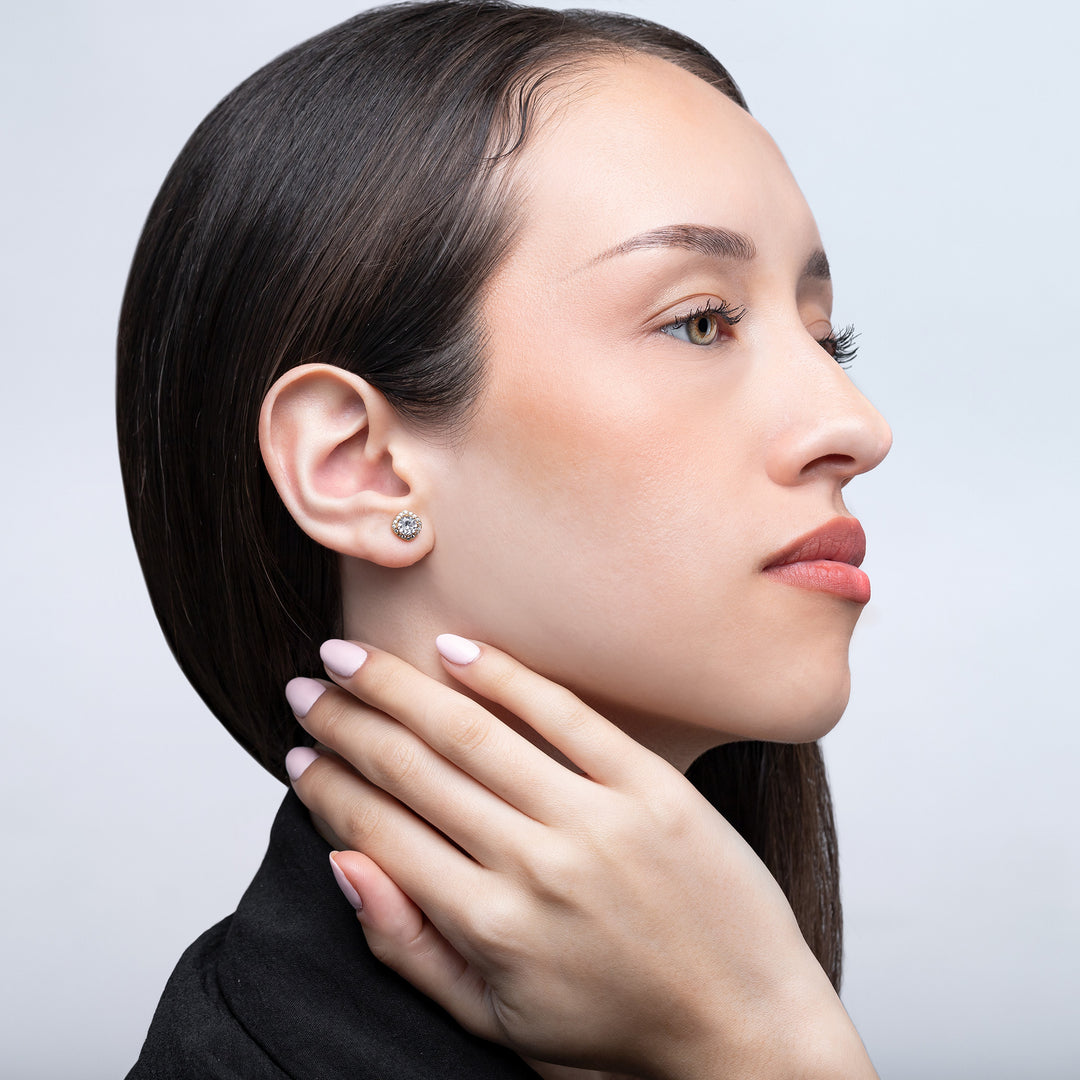 Close-up of a woman wearing a diamond earring on a light gray background