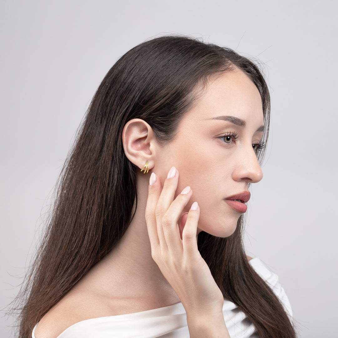 Woman wearing a gold earring on a plain background