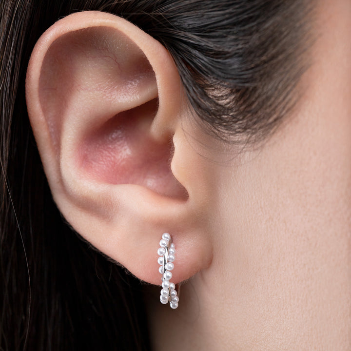 Close-up of an ear wearing a silver hoop earring with a blurred background