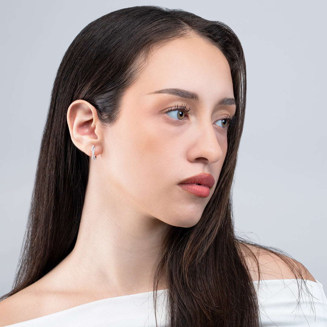 Woman with long dark hair wearing a white top against a light gray background