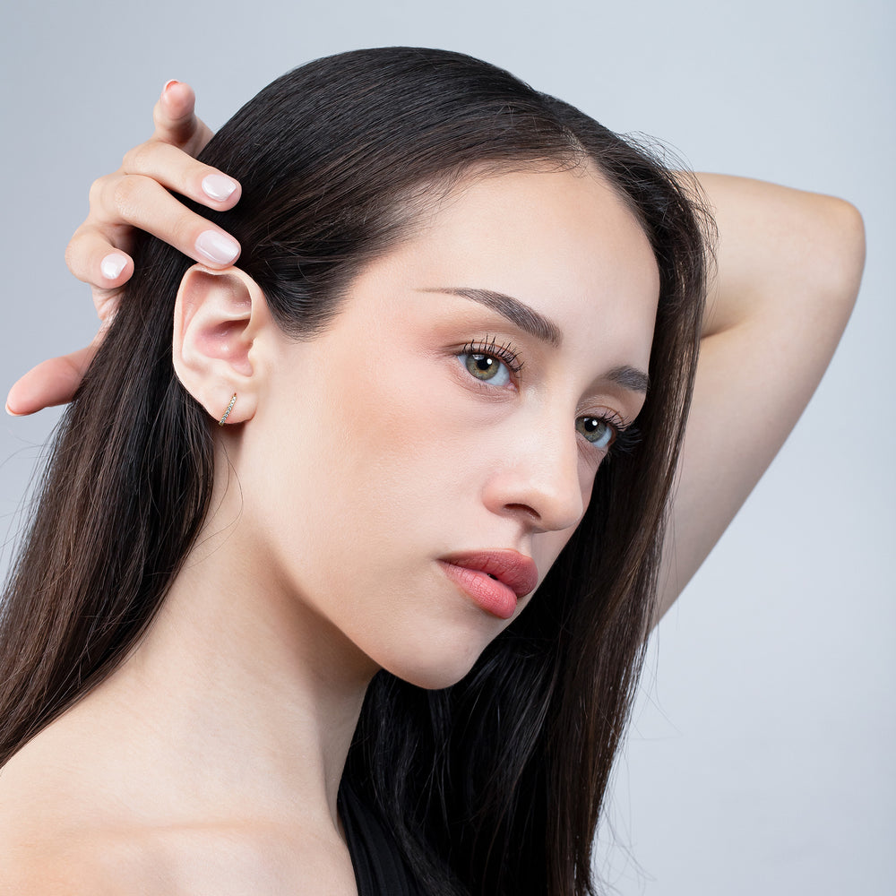 Woman with long dark hair touching her head against a light gray background
