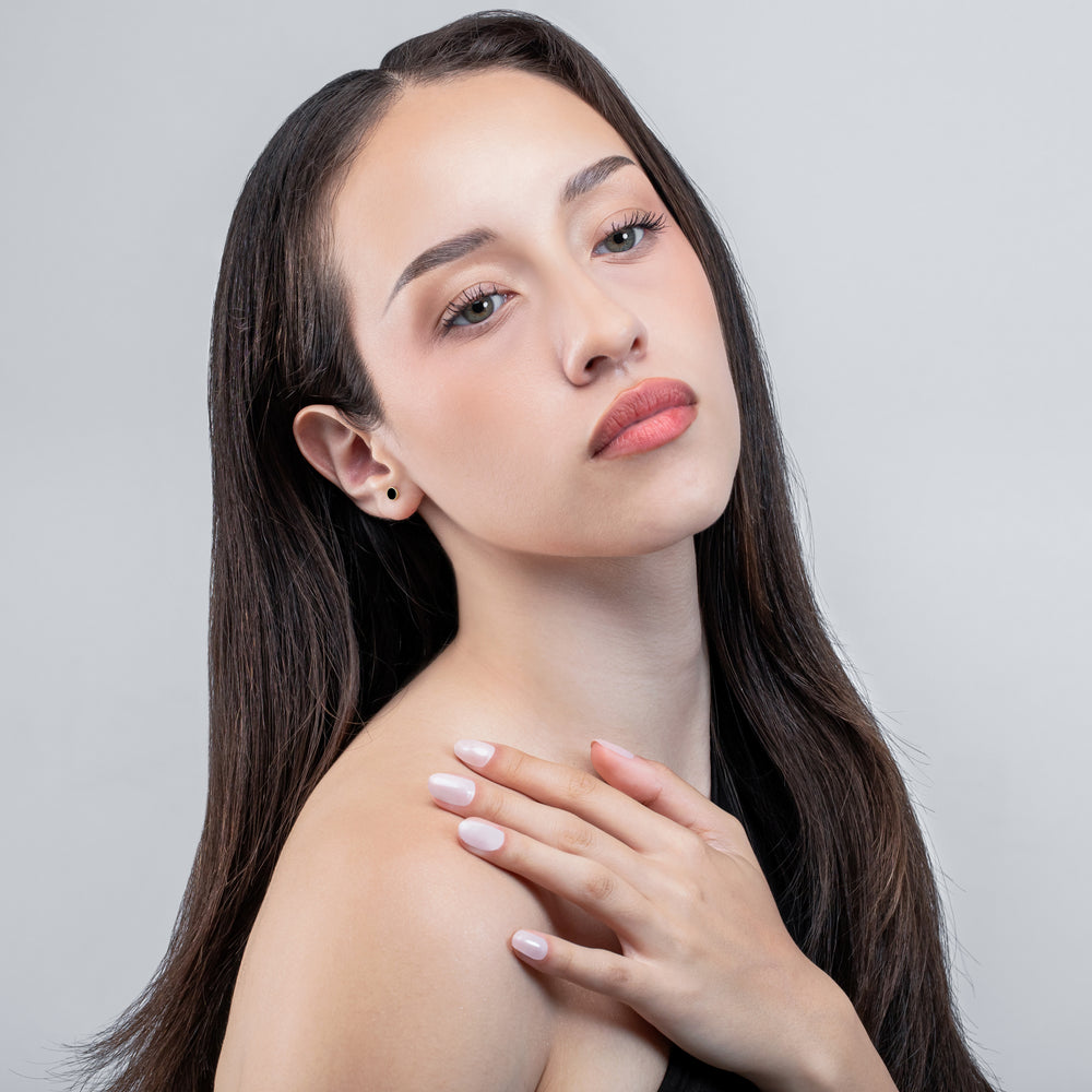 Woman with long dark hair and light makeup against a gray background