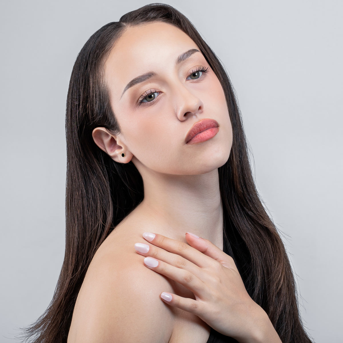 Woman with long dark hair and light makeup against a gray background