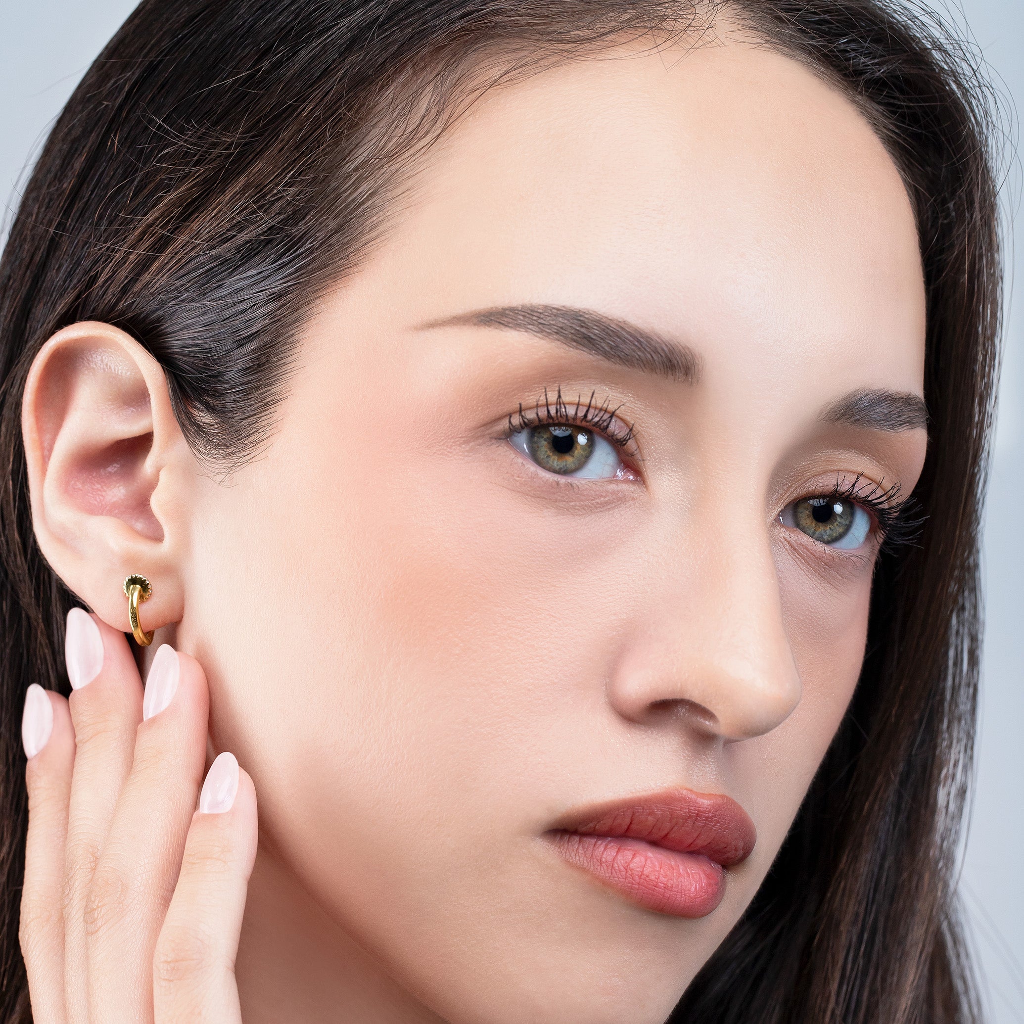 Close-up of a woman wearing an earring with a neutral background