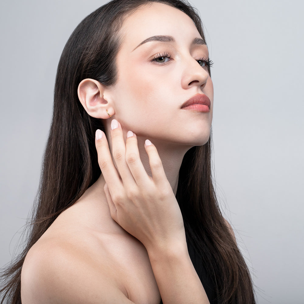 Woman touching her ear with a plain background