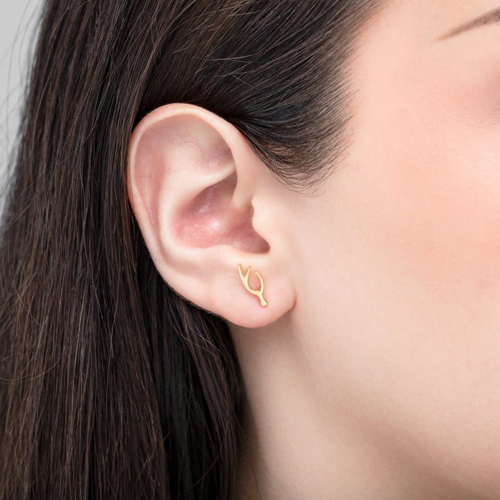 Gold earring worn by a person with dark hair.