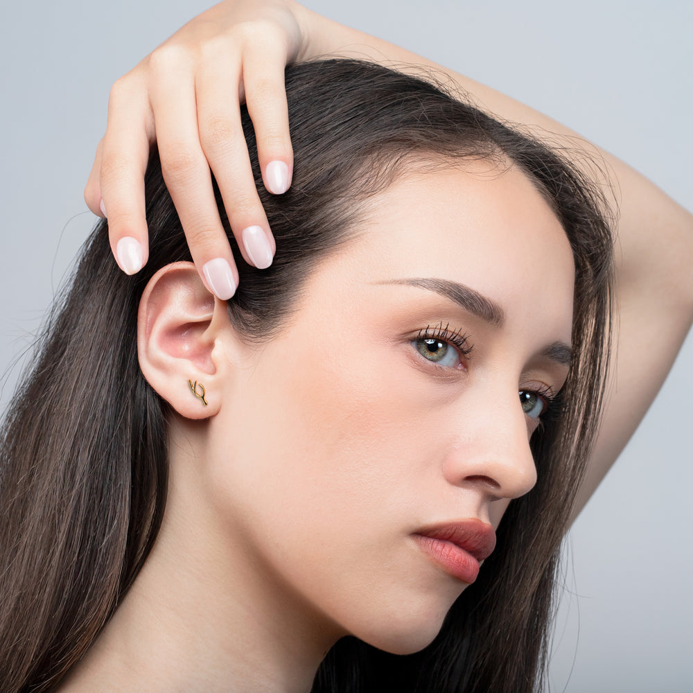 Close-up of a woman with one hand touching her hair against a gray background