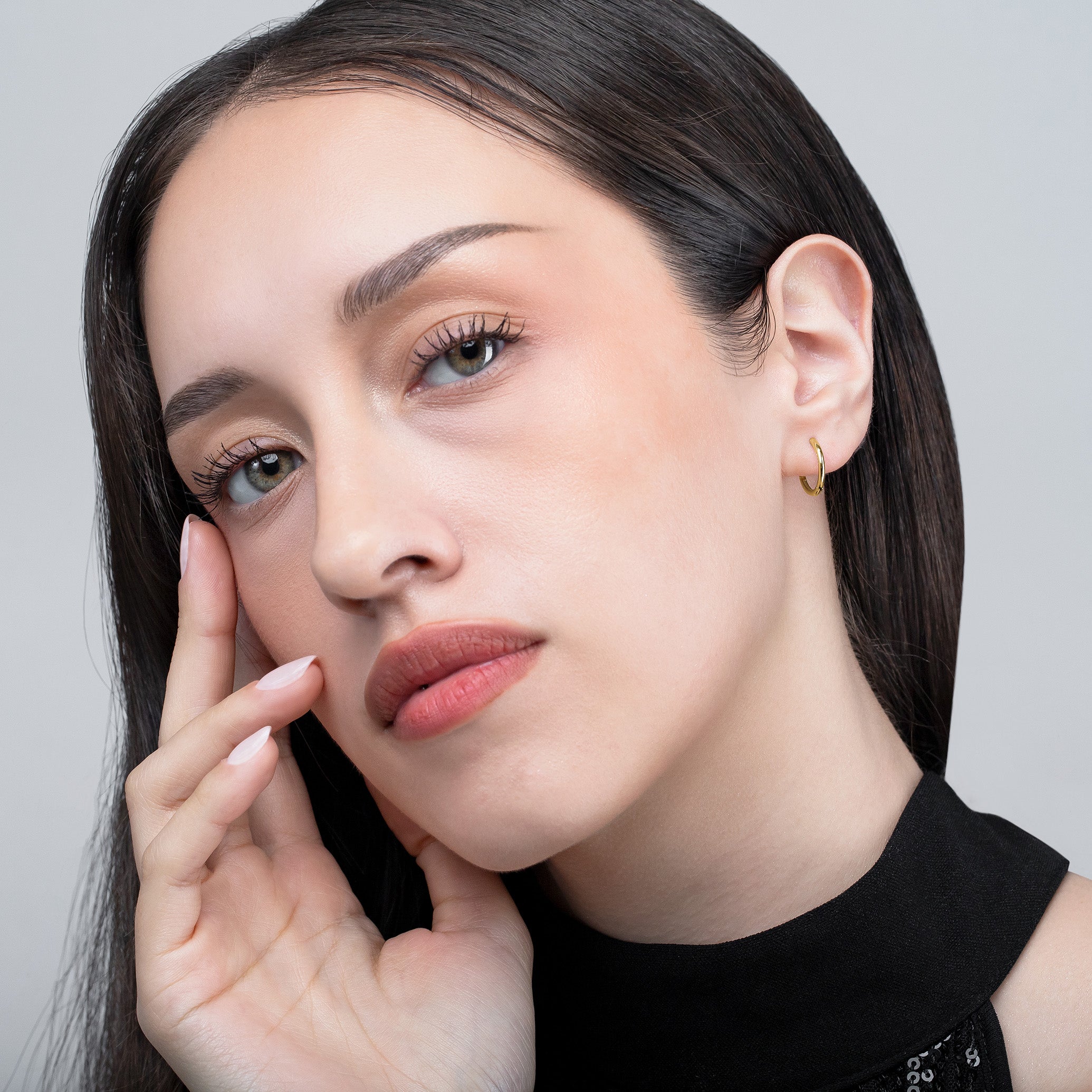 Woman with hand near face against a neutral background